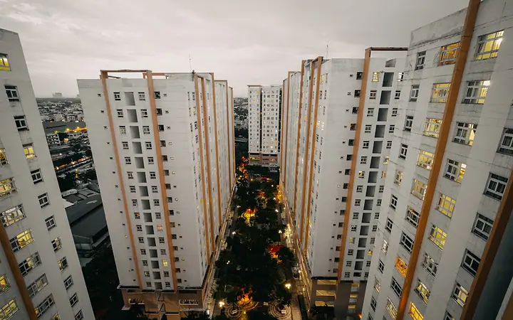 Torres de condomínio ao anoitecer, com as janelas acesas e uma árvore de Natal no centro
