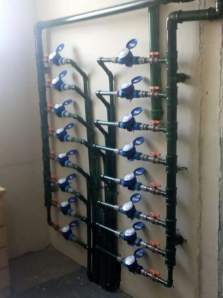 Coluna de hidrômetros individuais azuis instalados na tubulação de um shaft, um por apartamento