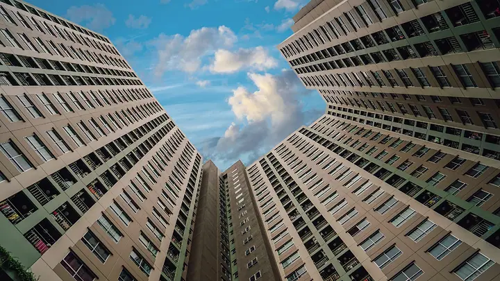 Torres de condomínio vistas de baixo, com céu azul e nuvens