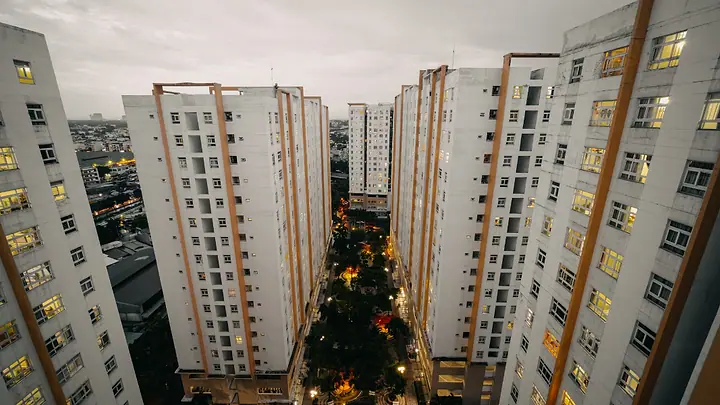 Torres de condomínio ao anoitecer, com as janelas acesas